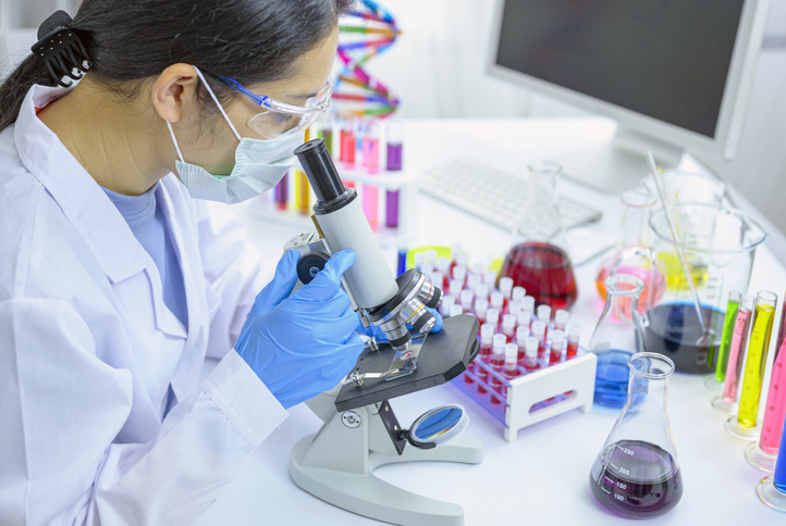 Woman scienist in laboratory. Scientist adjusting a microscope in a laboratory.