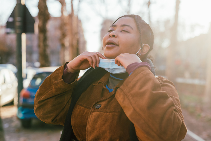 Young woman removing face mask outdoors
