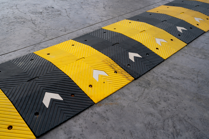 Speed bump on the road, yellow and black striped speed bump in asphalt road to slow down fast moving cars