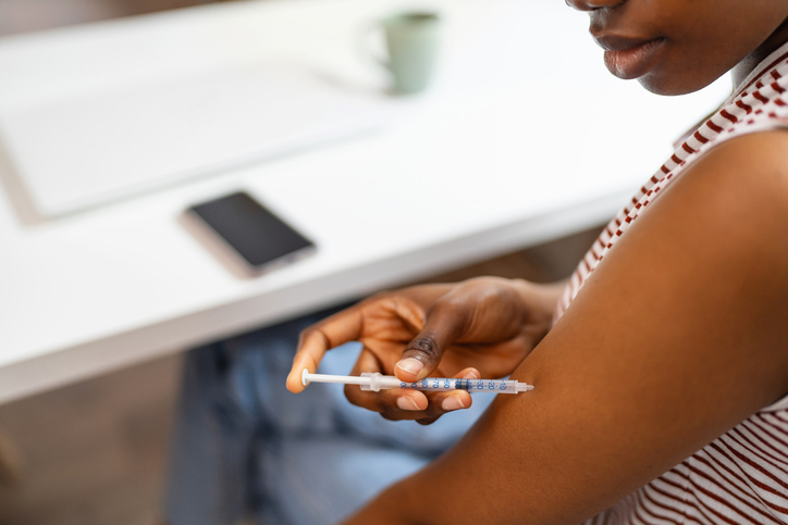 Young woman self-giving an insulin injection