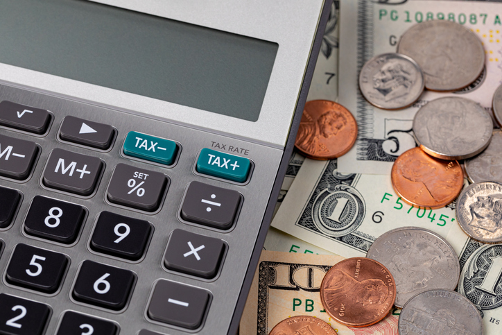 Tax calculator with cash money and coins. Income, sales tax and property taxes concept.